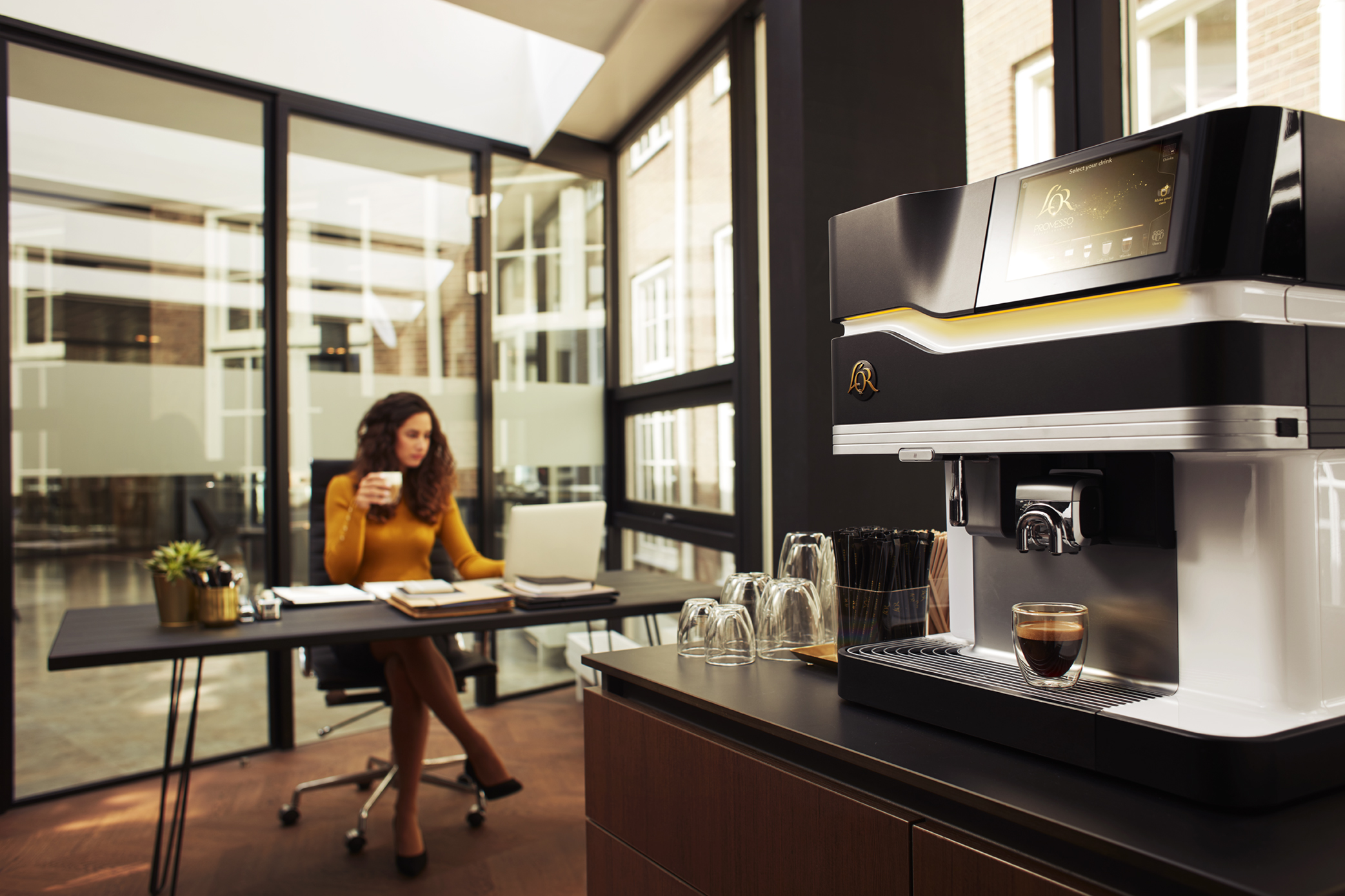 Mujer en escritorio tomando una taza de JDE café
